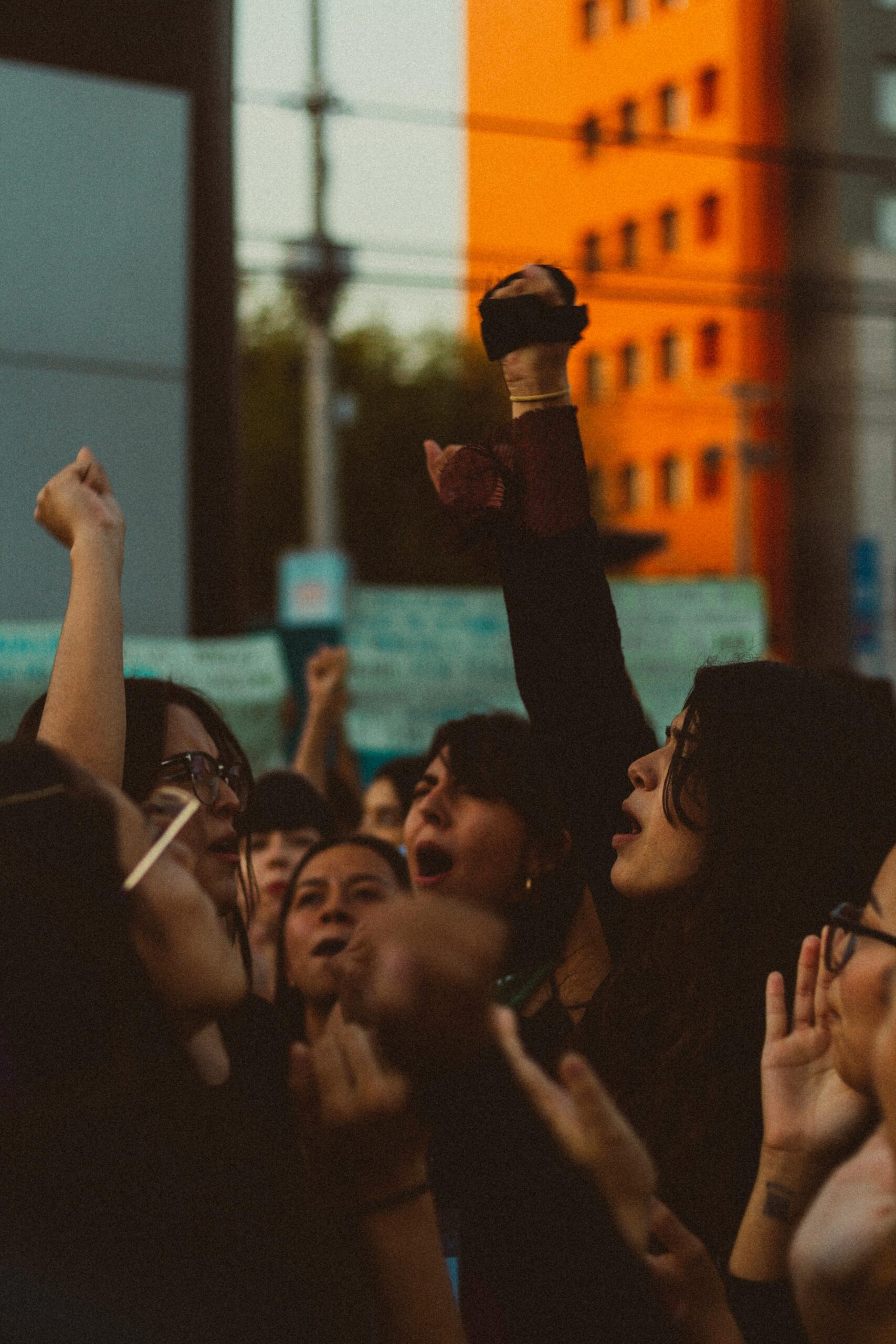 A blurred background image showing raised arms at what appears to be a public gathering or rally.