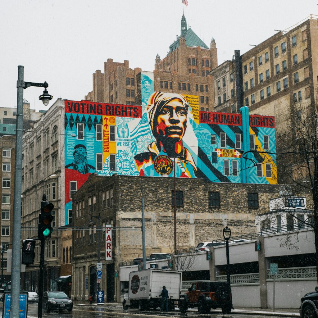 Large mural on the side of a city building featuring a portrait and the words “Voting Rights Are Human Rights.” 