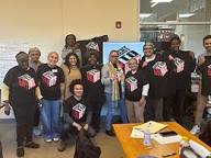 A group picture of people smiling. In the foreground, several wear a black “Right to The City Vote” T-shirt.